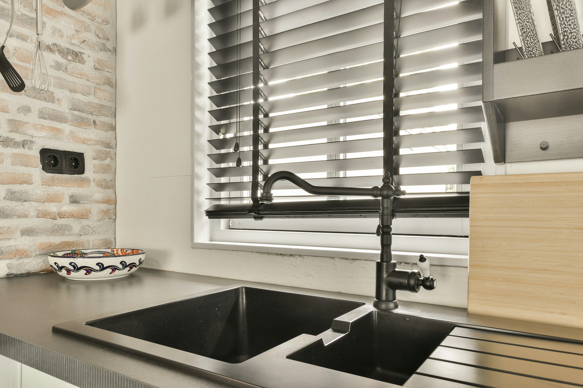 a kitchen sink under a window with white blinds